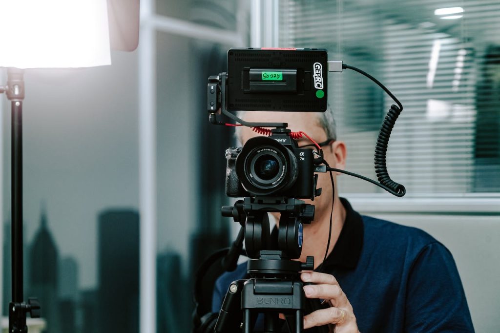A videographer setting up a camera with additional gear in a modern studio environment.